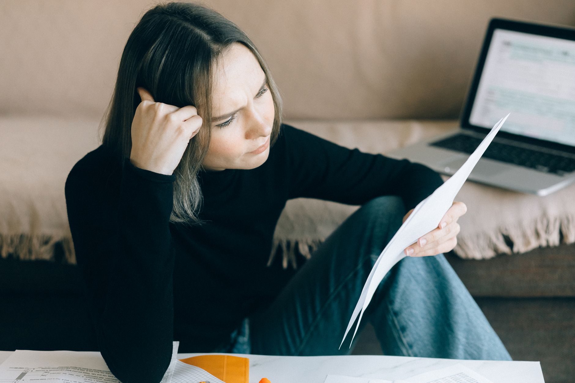 Woman looking at a credit report on a laptop in her living room.