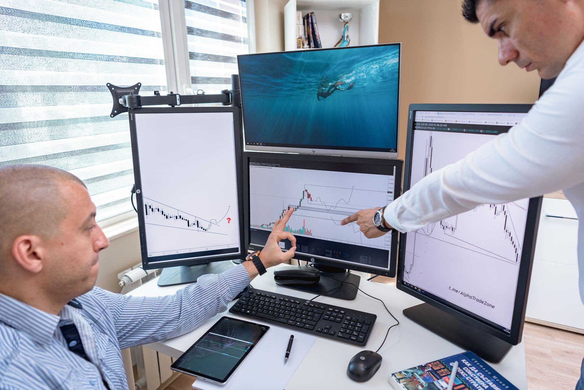 A person reviews colorful data charts on large monitors at a desk.