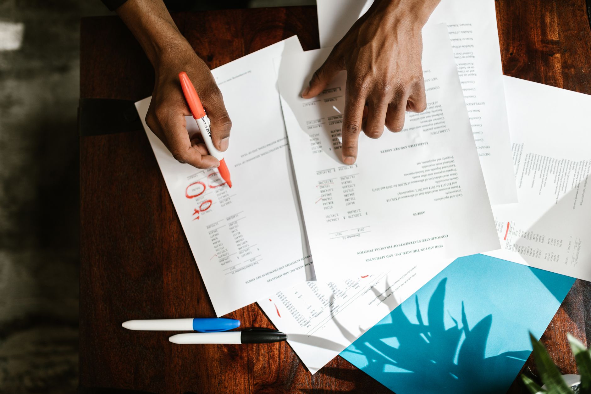 Person reviewing a printed list of old online accounts at a tidy desk with a laptop and notebook.