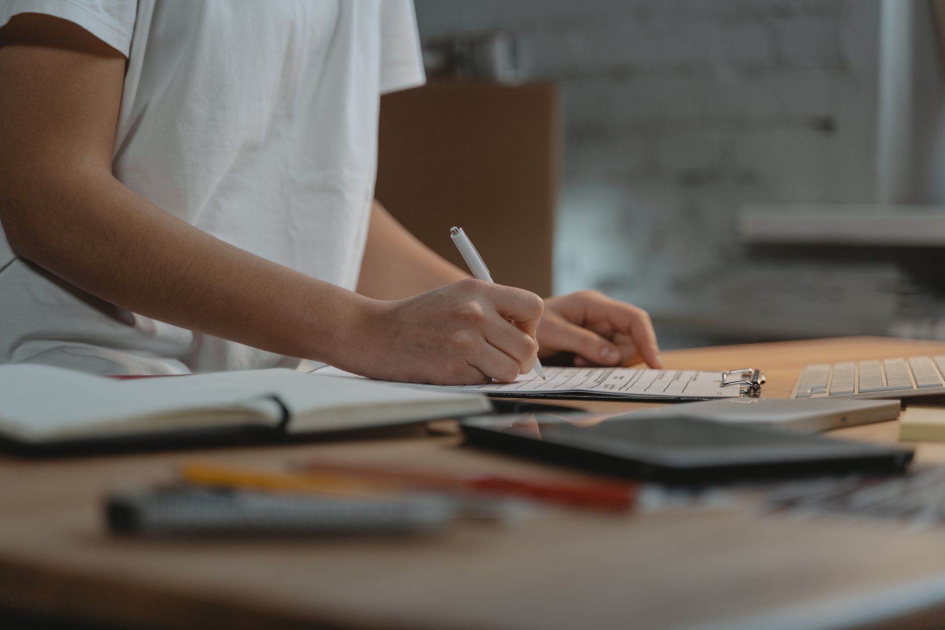 A person at a tidy desk writing a privacy checklist next to a laptop and smartphone.