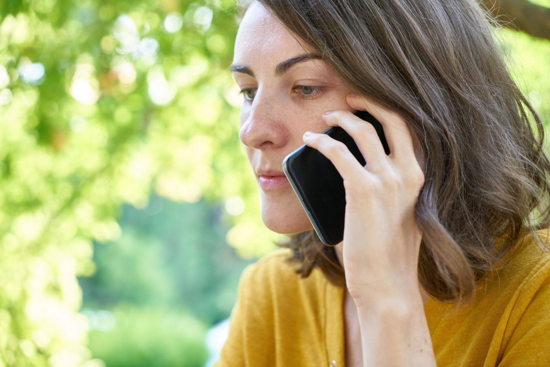 Person looking at smartphone and declining an incoming call while sitting on a couch.