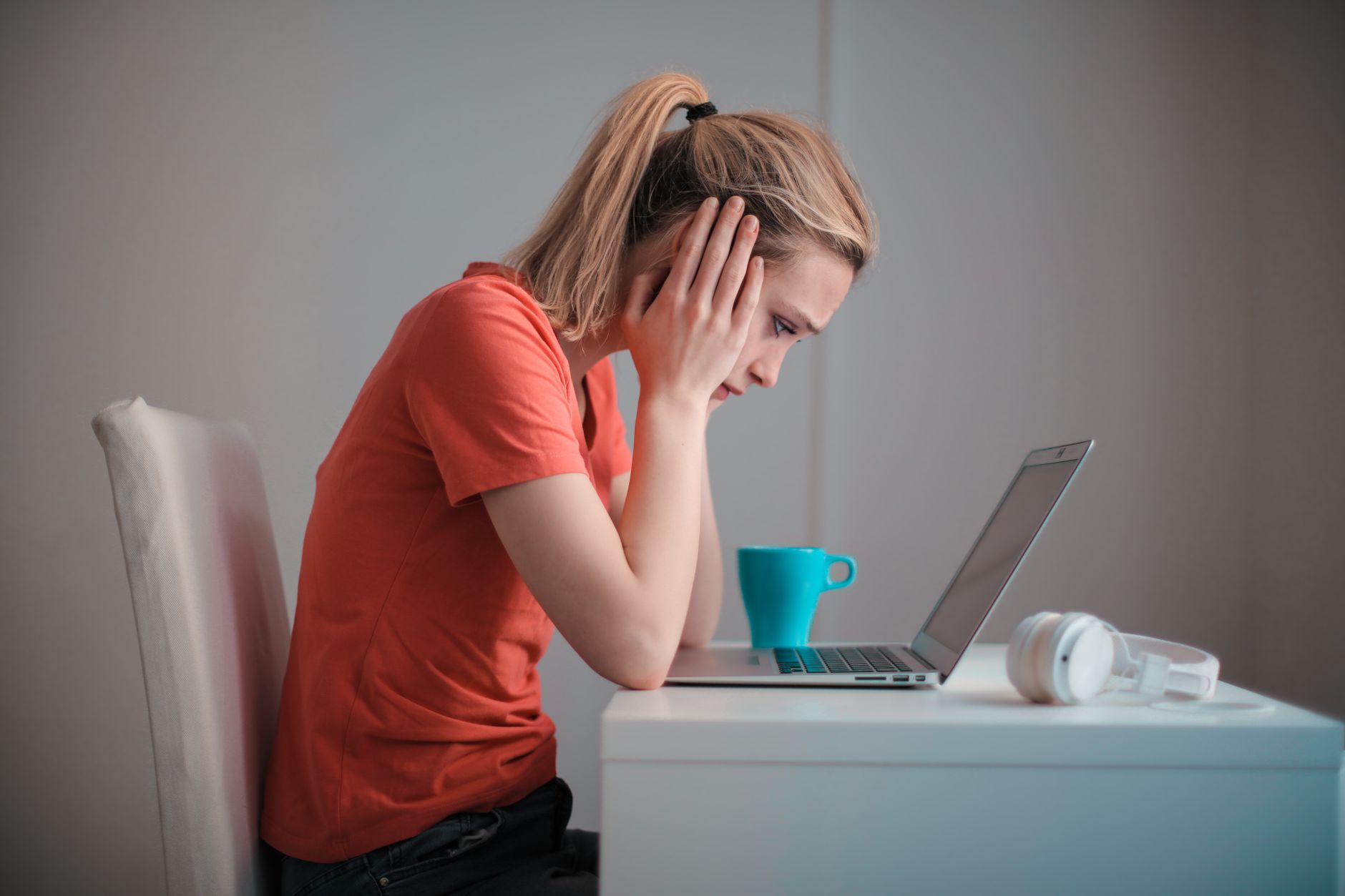 Person looking at a laptop screen showing many email notifications while sitting at a home desk, appearing concerned about inbox clutter.