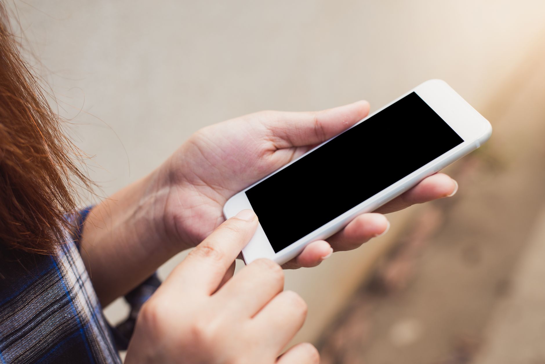 A person holding a smartphone and placing a finger on the fingerprint sensor.