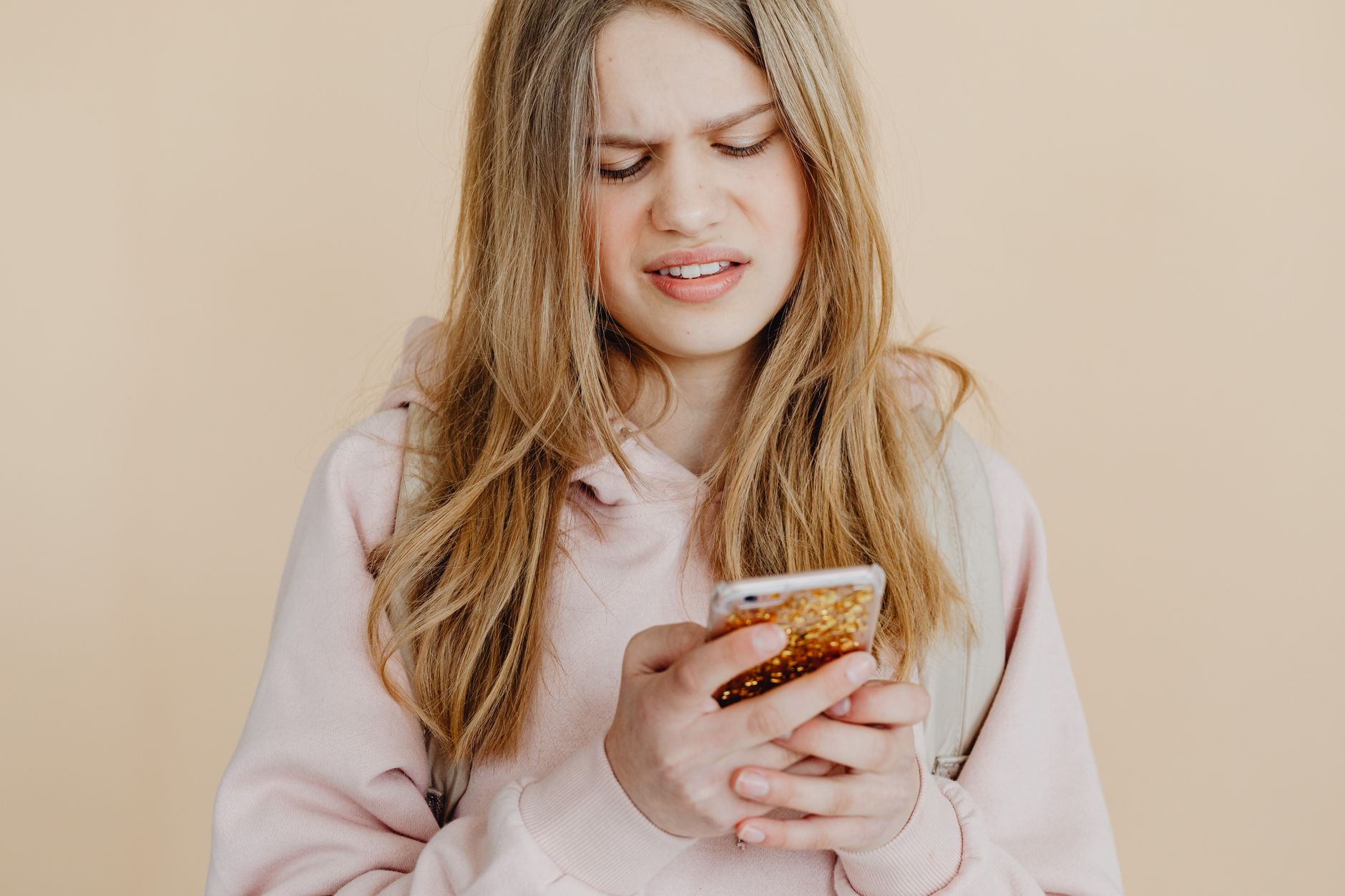 A person holds a smartphone and squints at a strange text message with a concerned face.