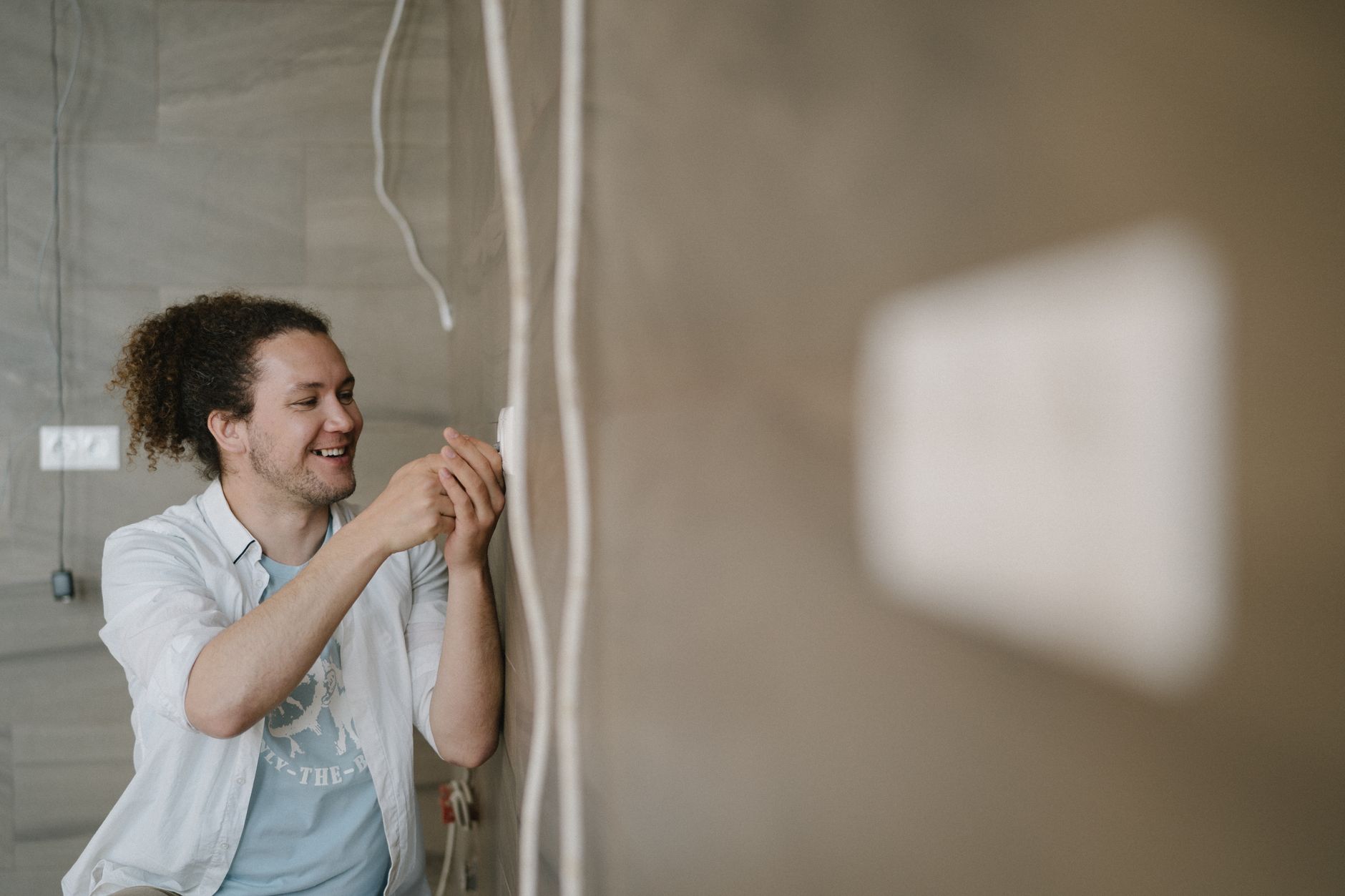 A hand flipping several physical toggle switches on a wall panel, with some up and some down